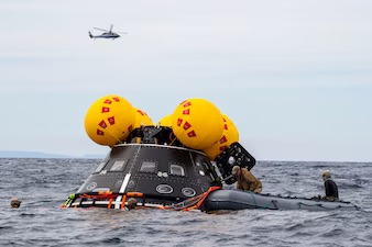 Navy divers assigned to EOD Mobile Unit (EODMU) 1, Inflate a NASA “front porch” life raft
